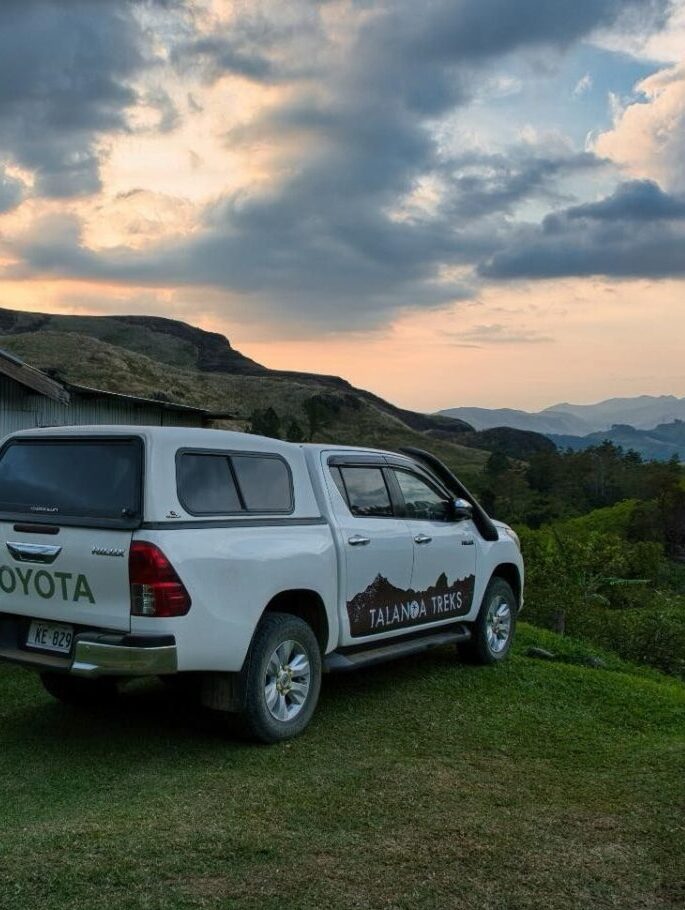 A Talanoa Treks truck parked at sunset with hills in the background