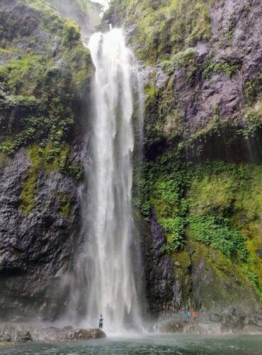 Nabalesere waterfall with small figures of people standing at its base